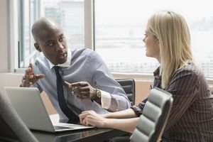 man and woman talking in front of a computer