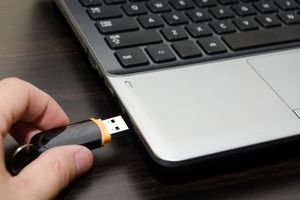 Picture of a hand inserting a USB key into the USB port of a laptop