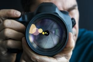 Man holding camer, close-up of lens