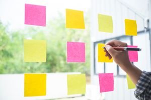 Cropped hand of businessman writing on adhesive note