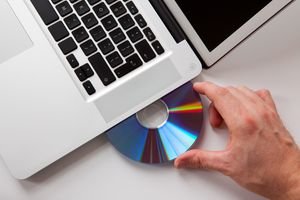 Photo of a hand inserting a disc into a laptop computer