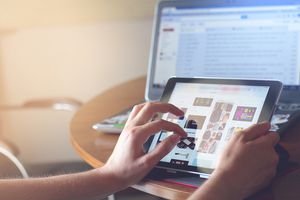 Person using ipad in front of laptop