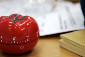 Tomato shaped timer with blurred papers in the background