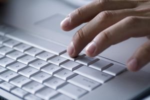 Hand typing on laptop computer, close-up