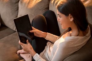 Woman sits on couch with tablet