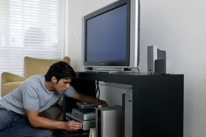 Mid adult man fixing television cable, side view