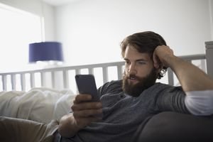 Man texting with cell phone on sofa