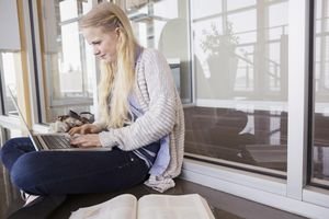 High school student using laptop on floor