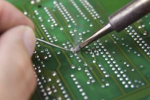 'Electronic technician soldering on a circuit board, close up pho'