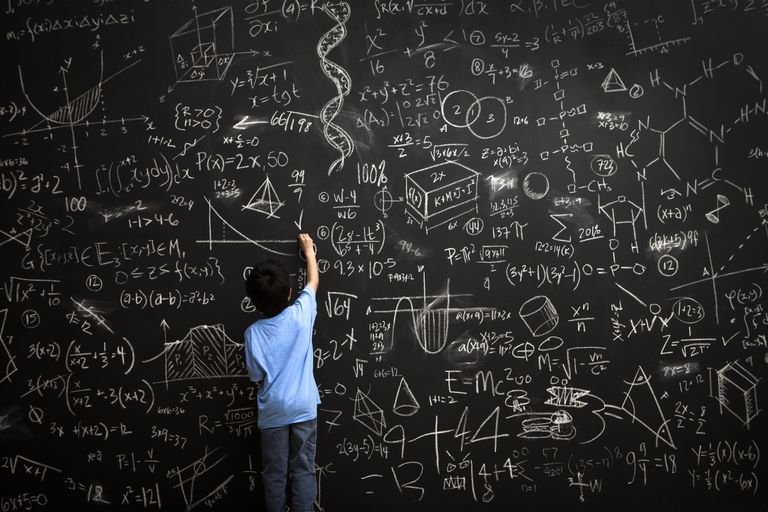 Photo of a boy writing math equations on a chalkboard
