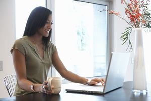 Young woman with coffee using laptop