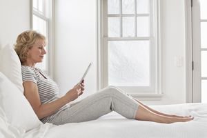 A woman in bed using an ipad.