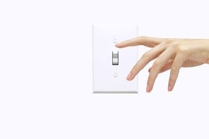 Hand of woman pressing light switch