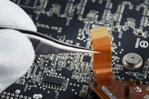 Human hand repairing printed circuit board, close up