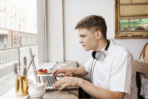 Young man working on laptop in cafe