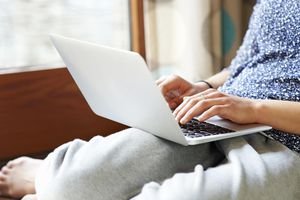 Woman using laptop at home, close up