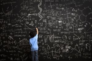 Photo of a boy writing math equations on a chalkboard
