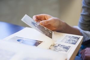 A woman's hand holding up an old photograph above a photo album